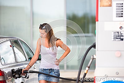 Attractive, young woman refueling her car in a gas station Stock Photo