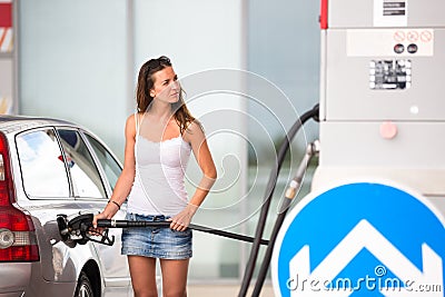 Attractive, young woman refueling her car in a gas station Stock Photo