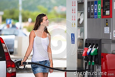 Attractive, young woman refueling her car in a gas station Stock Photo