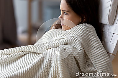 Attractive young woman relaxing under soft blanket in comfortable chair Stock Photo