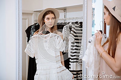 Attractive young woman trying on dress in front of mirror Stock Photo