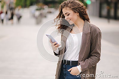 Attractive young woman use phone in city. Happy beautiful woman writing massage on phone, online Stock Photo