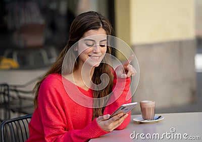 Attractive young woman using smart mobile phone dating app in a coffee shop outside terrace Stock Photo