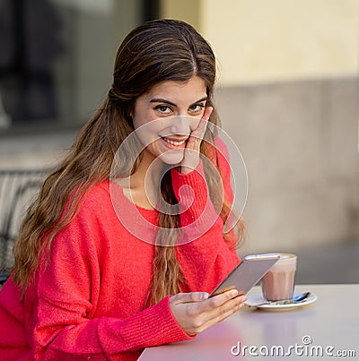 Attractive young woman using smart mobile phone dating app in a coffee shop outside terrace Stock Photo