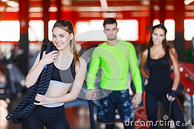 An attractive young woman standing in a fitness center posing with a physical rope over her shoulder. Stock Photo