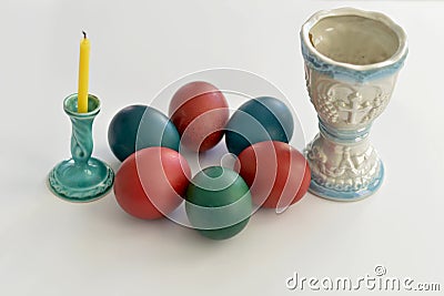 Easter eggs laid on a table next to a non-lit candle and a lamp Stock Photo