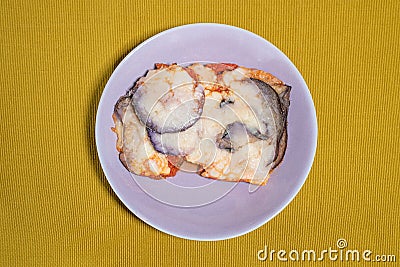 Aubergine parmigiana served in a lilac colored dish placed on a light green table runner Stock Photo