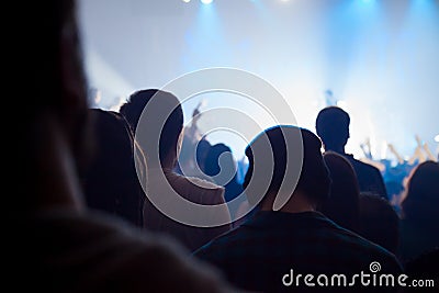 Audience silhouettes crowd in large concert hall watching rock show. Editorial Stock Photo