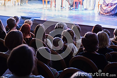 The audience in the theater watching a play. The audience in the hall: adults and children Editorial Stock Photo