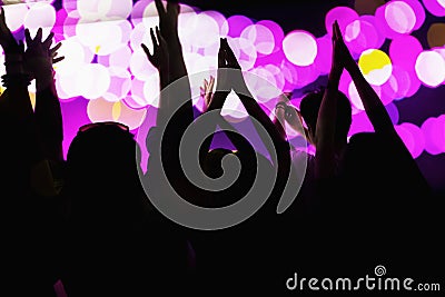 Audience watching a rock show, hands in the air, rear view, stage lights Stock Photo