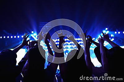 Audience watching a rock show, hands in the air, rear view, stage lights Stock Photo