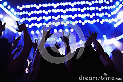 Audience watching a rock show, hands in the air, rear view, stage lights Stock Photo