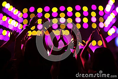 Audience watching a rock show, hands in the air, rear view, stage lights Stock Photo