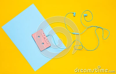 Audio cassette and earphones on a blue yellow pastel background. Musical concept. Retro style. Minimalism. Top View. Stock Photo