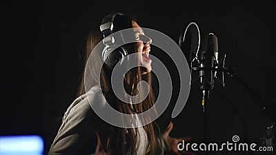 Audio recording studio. Woman with headphones and studio microphone singing. Stock Photo