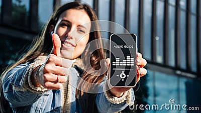 Audio tour online app on digital mobile smartphone. Happy young student woman holding phone listening audioguide Stock Photo