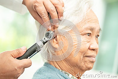 Audiologist or ENT doctor use otoscope checking ear of asian senior woman patient treating hearing loss problem Stock Photo