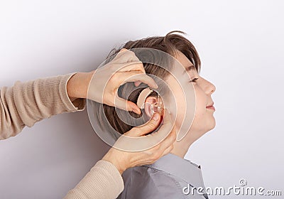 Audiologist fitting hearing aid on a smilling young boy Stock Photo