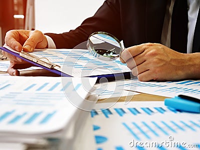 The auditor makes audit and verifies the report using a magnifying glass Stock Photo