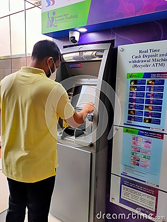 25 Aug 2020, Dhaka, Bangladesh. An asian male wearing mask using ATM machine for withdrawal of money Editorial Stock Photo