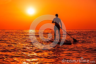 August 4, 2021. Anapa, Russia. Male athlete on paddle board at sea with sunset or sunrise. Man on Red Paddle sup board Editorial Stock Photo