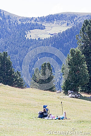 Family rests lying on a green meadow, Val di Funes - Italy Editorial Stock Photo