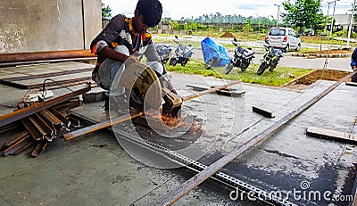 August 2018,Kolkata, India, A male worker cutting steel bar with motorized Bosch Steel Rod Cutter and generating sparks Editorial Stock Photo