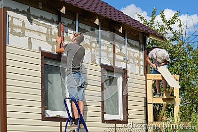 August 6, 2017: Photo of two workers cover the facade Editorial Stock Photo