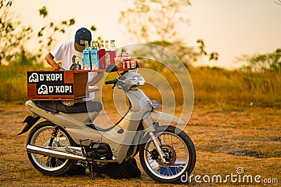 August 08, 2023. Surabaya, Indonesia. Barista on bike selling drinks during sunset in a hill forest. Editorial Stock Photo