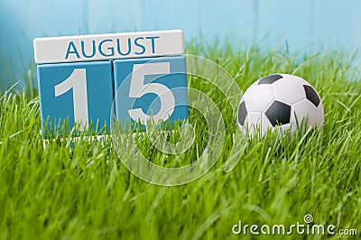 August 15th. Image of august 15 wooden color calendar on green grass lawn background with soccer ball. Summer day. Empty Stock Photo