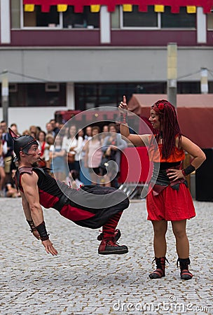 02 August 2019 - Young woman pointing up and man suspended in the air on a street circus performance during a medieval event Editorial Stock Photo