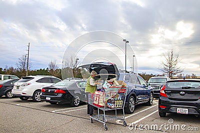 Senior putting groceries in her car wearing a face mask side view Editorial Stock Photo