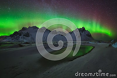 Aurora Borealis green reflection over the water at Stokksnes Stock Photo