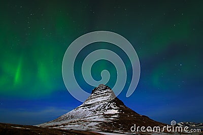 Aurora Borealis from Iceland. Beautiful green Northern Lights on the dark blue night sky with peak with snow, Kirkjufell Stock Photo