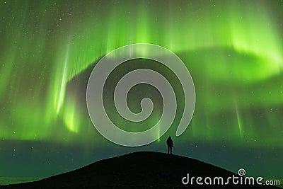 Aurora borealis and silhouette of standing man. Jokulsarlon, Iceland. Aurora and happy man. Sky with stars and green polar lights. Stock Photo