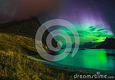 Aurora over sandy beach haukland, Kvalvika and Skagsanden with stones in Norway, Lofoten islands. Northern lights in Stock Photo