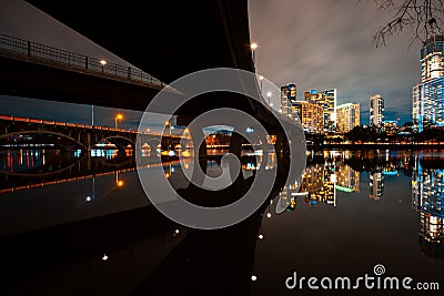 Austin skyline at night and Lamar pedestrial Bridge with bright illuminated buildings reflecting in Lady Bird Lake Stock Photo