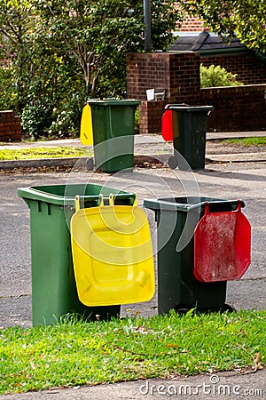 Australian garbage wheelie bins with colourful lids for general and recycling household waste lined up on the street kerbside Stock Photo