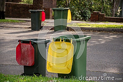 Australian garbage wheelie bins with colourful lids for general and recycling household waste lined up on the street kerbside Stock Photo