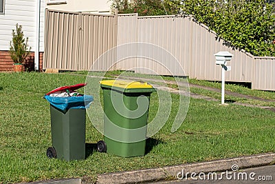 Australian garbage wheelie bins with colourful lids for general and recycling household waste on the street kerbside Stock Photo