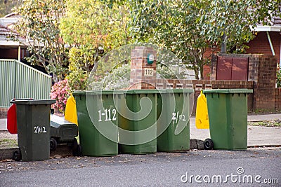 Australian garbage wheelie bins with colourful lids for recycling and general household waste lined up on the street kerbside Stock Photo