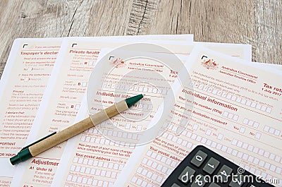 Australian tax forms with pen and calculator on a wooden table Editorial Stock Photo