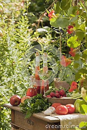 Austria, Salzburger Land, Vegetables, fruits and herbal essences in bottle on table in garden Stock Photo