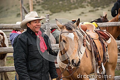 Western cowboy with saddled buckskin horse ready to go roundup horses Stock Photo