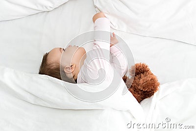 Authentic portrait cute caucasian little infant chubby baby girl or boy in pink sleepy upon waking with teddy bear Stock Photo