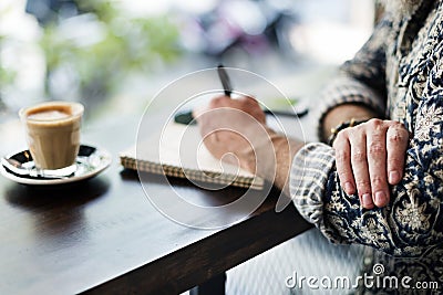 An author making notes in a coffee shop Stock Photo