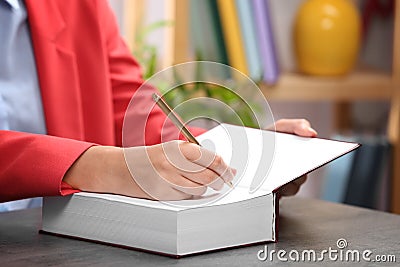 Author signing autograph in book at table indoors, closeup Stock Photo