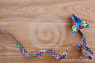 Autism awareness day or month. Paper plane in origami style with autism awareness puzzle ribbon on wooden background. Stock Photo