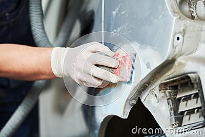 Auto repairman plastering and sanding autobody bonnet Stock Photo