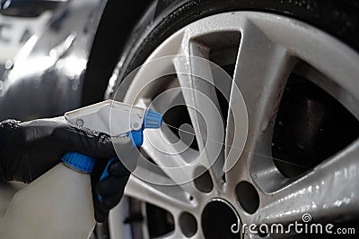 Auto detailing worker applies chemistry to wheels. Professional car wheel wash. Stock Photo